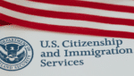 U.S. flag draped above a document that shows the text 'U.S. Citizenship and Immigration Services' and the agency seal.
