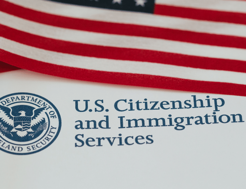 Navigating New Citizenship Rules: What Trump’s Executive Orders Mean for Surrogacy Blog Post Image 081426 - Conceptual Options Surrogacy Agency and Egg Donation Agency U.S. flag draped above a document that shows the text 'U.S. Citizenship and Immigration Services' and the agency seal.
